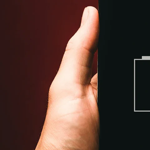 A phone showing an empty battery icon in a user's hand.