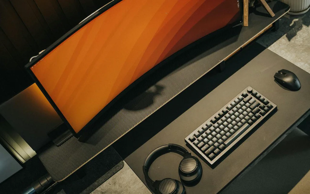 Écran gaming ultrawide sur un bureau soigné avec clavier mécanique, souris et casque.