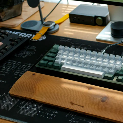 Premium desk setup with a mechanical keyboard, monitor, mouse and wooden wrist rest.