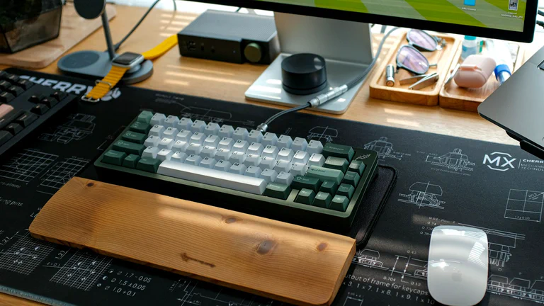 Premium desk setup with a mechanical keyboard, monitor, mouse and wooden wrist rest.