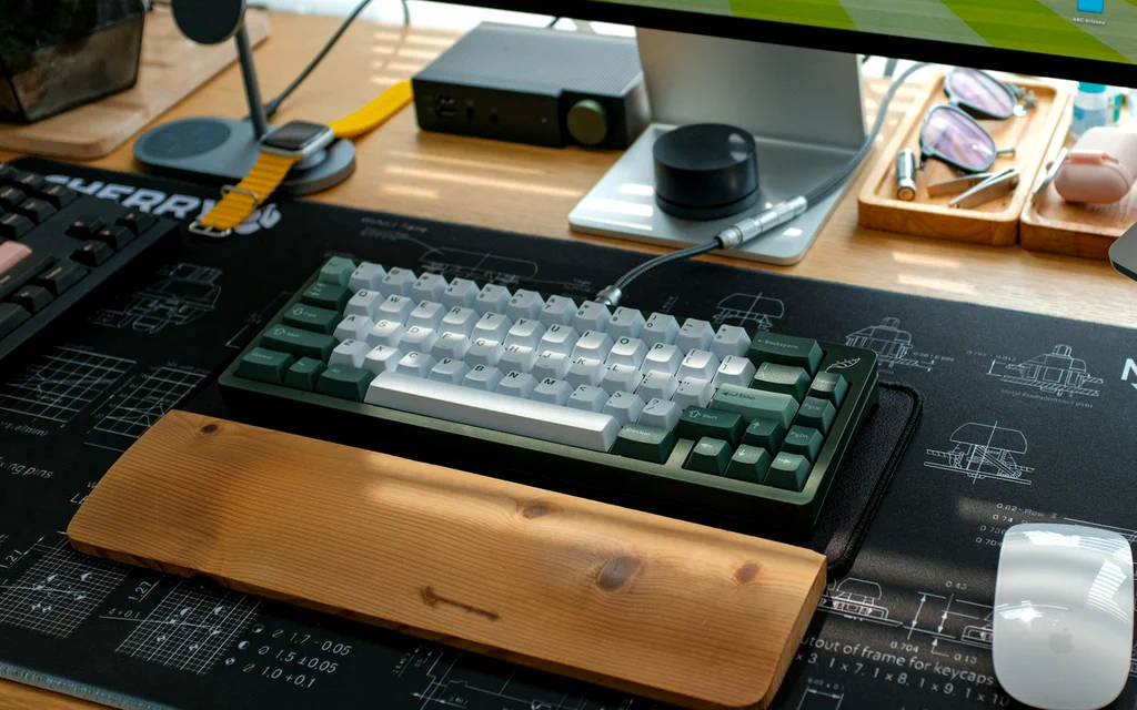 Premium desk setup with a mechanical keyboard, monitor, mouse and wooden wrist rest.