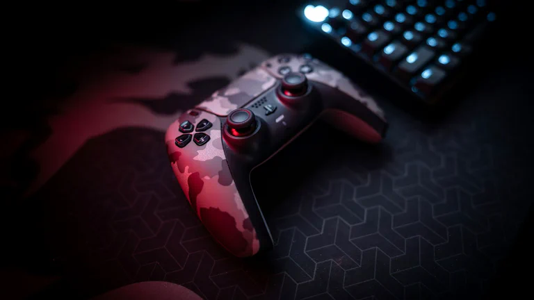 Game controller and keyboard on a dark gaming desk.