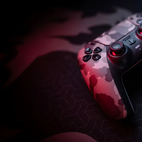 Game controller and keyboard on a dark gaming desk.