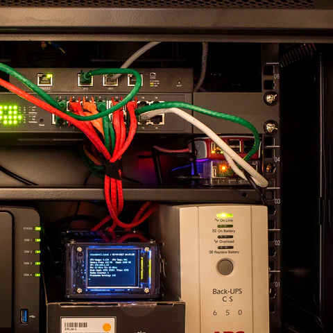 Armoire réseau domestique avec un switch, un NAS, un petit routeur et un onduleur (UPS).
