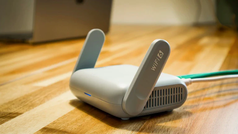 Gros plan sur un routeur Wi-Fi domestique posé sur un bureau avec un câble Ethernet branché.