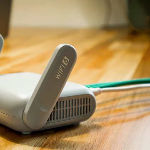 Primer plano de un router Wi-Fi doméstico sobre una mesa con un cable Ethernet conectado.