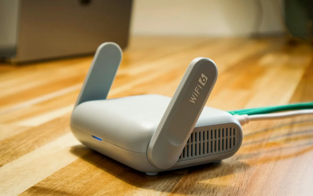 Gros plan sur un routeur Wi-Fi domestique posé sur un bureau avec un câble Ethernet branché.