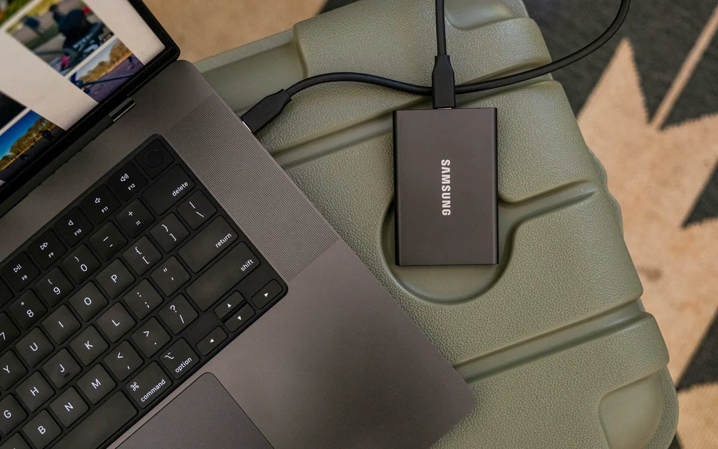 Portable external SSD connected to a laptop for file backup and storage planning.