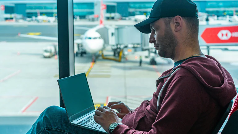 Traveler using a laptop at an airport before choosing a VPN service.