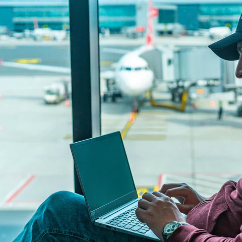 Voyageur utilisant un ordinateur portable dans un aéroport avant de choisir un service VPN.